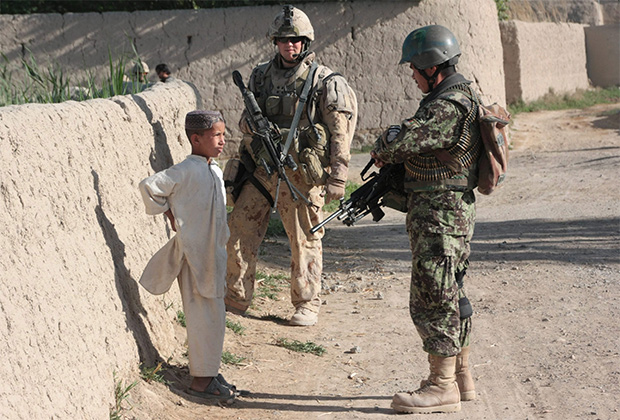 Солдаты говорят с афганским мальчиком, пока их сослуживцы за кадром допрашивают его спутника