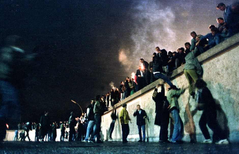 Восточные немцы перебираются через Берлинскую стену у Бранденбургских ворот после открытия границы с ФРГ. 10 ноября 1989 года