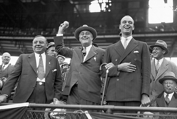 Губернатор Нью-Йорка и кандидат в президенты Франклин Рузвельт вбрасывает мяч в бейсбольном матче между Чикаго Кабс и Нью-Йорк Янкиз. Справа его сын Джеймс, слева мэр Чикаго Антон Чермак, 1932 год
