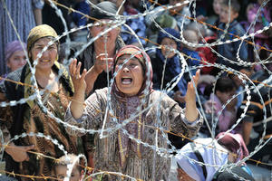 Uzbek woman Matluba, centre, who says she fled from the southern Kyrgyz city of Osh after her family were killed, weeps as she stands in line in no-man's-land near the Uzbek village of Jalal-Kuduk waiting for permission to cross into Uzbekistan, Monday, June 14, 2010. Many thousands of refugees fled a pogrom that began last week in southern Kyrgyzstan.