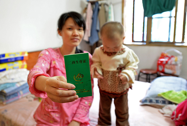 Женщина демонстрирует сертификат, дающий право на второго ребенка
