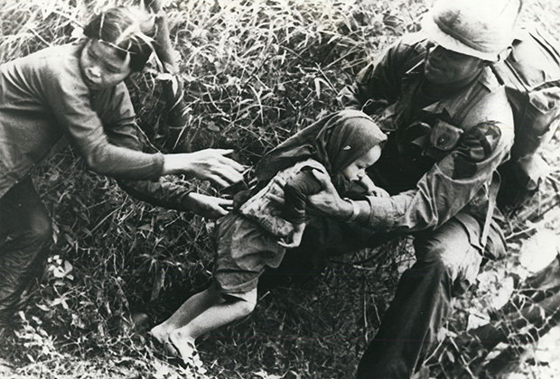 Американский пехотинец помогает бежать женщине и ребенку из района боевых действий во Вьетнаме, 1967 год