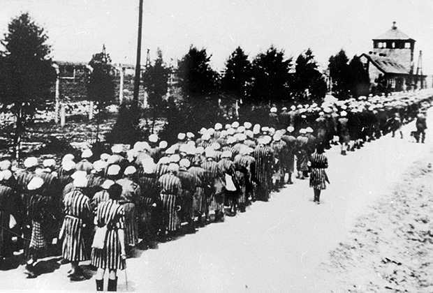 Женщины-заключенные под конвоем возвращаются в концлагерь Аушвиц после принудительного труда на оружейной фабрике, 1942 год