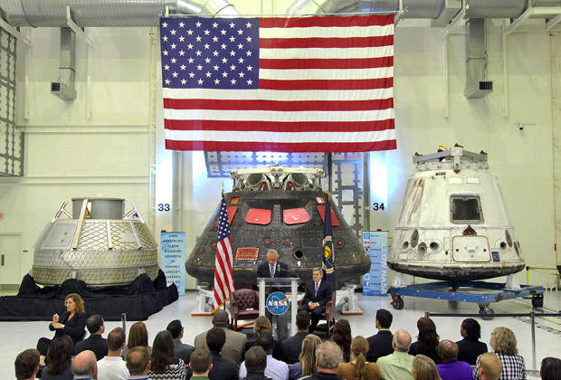 Глава НАСА Чарльз Болден и директор Космического центра Кеннеди Боб Кабана на фоне прототипов разрабатываемых пилотируемых космических кораблей Orion, Dragon V2 и CST-100