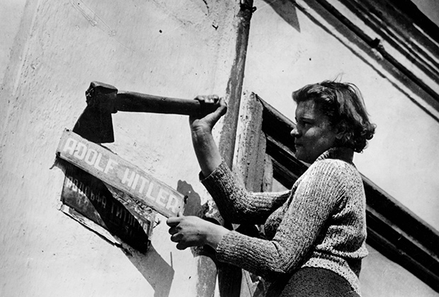 Женщина снимает табличку с надписью «Адольф Гитлер». Конец Второй мировой войны