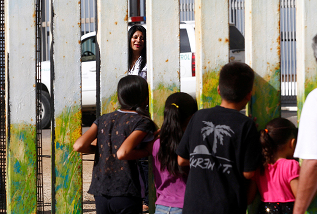 В парке Сан-Диего мать разговаривает через забор с детьми, находящимися в Тихуане