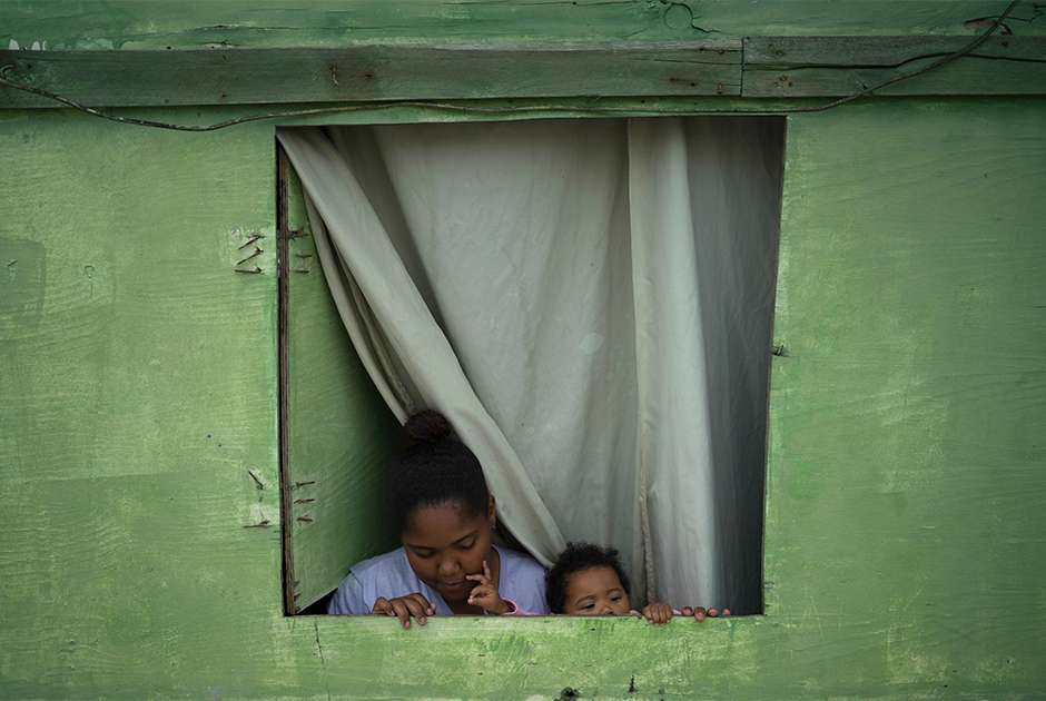 Одинокая мать с дочерью в своей деревянной хижине. Когда на улицах начинают стрелять, они бегут в соседский кирпичный дом.