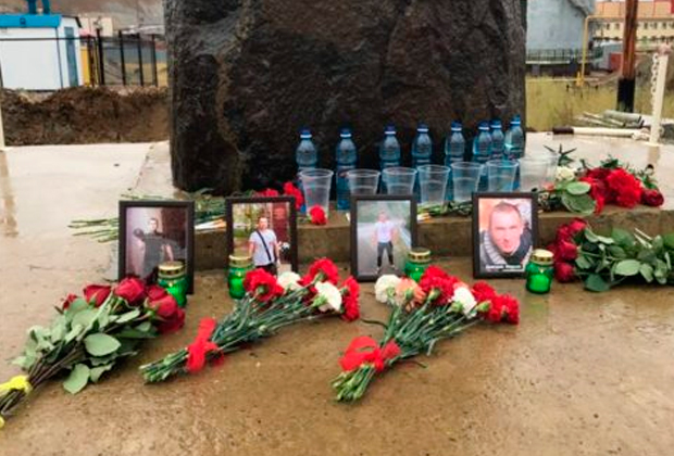 Люди приносят цветы к памятному камню у рудника «Мир», чтобы почтить память погибших шахтеров