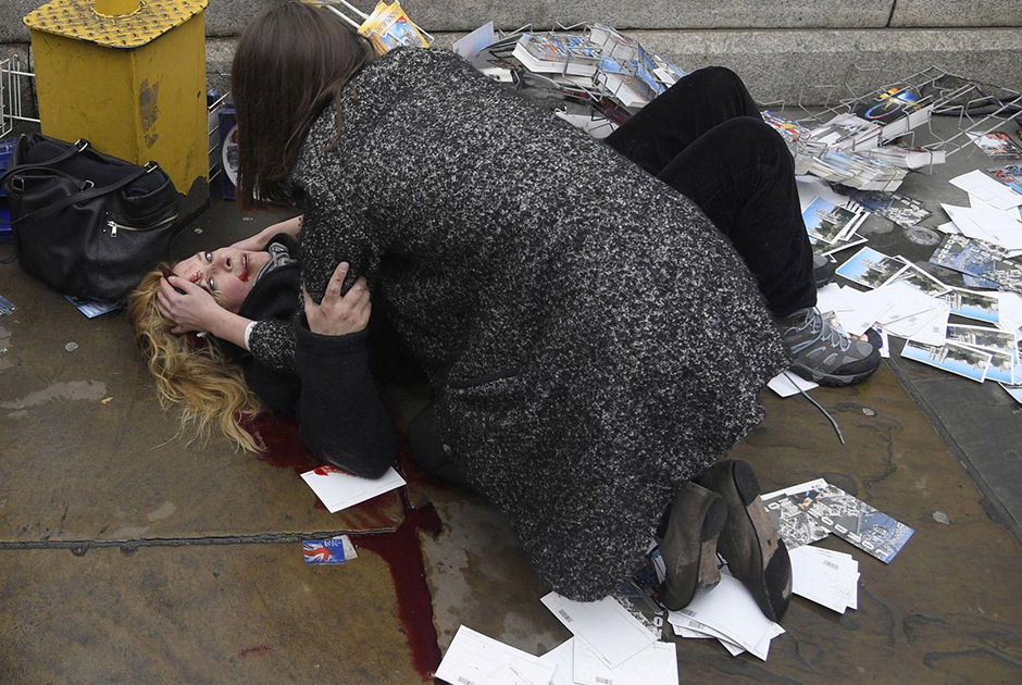 Прохожая пытается успокоить женщину, пострадавшую от наезда машины на пешеходов на Вестминстерском мосту в Лондоне. Под колесами автомобиля, управляемого террористом Халидом Масудом, погибли пять человек. 