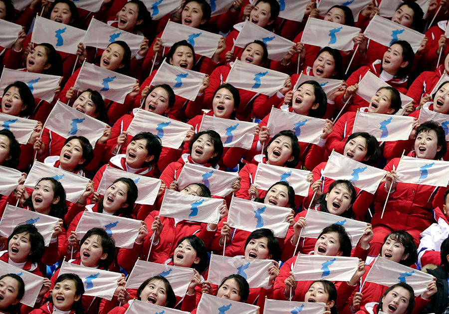 Болельщицы из Северной Кореи. В руках каждой флажок с Корейским полуостровом. За плечами — бдительный сосед. 