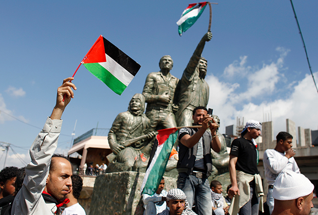 Сирийцы с палестинскими флагами около Голанских высот, завоеванных Израилем у Сирии