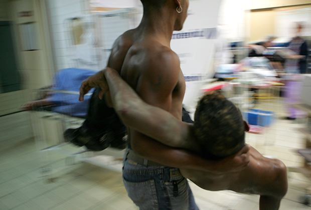 Венесуэлец несет раненого друга в отделение скорой помощи