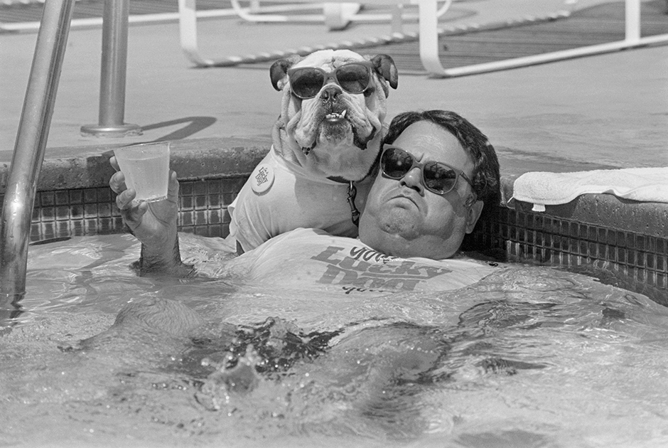 Джон Биссилья расслабляется в бассейне со своим английским бульдогом Айком. Пара участвует в конкурсе Lucky Dog Look-Alike с призовым фондом 10 000 долларов.  