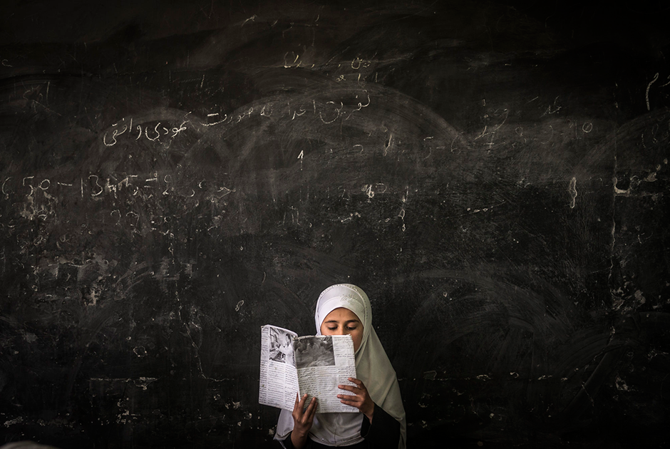 Афганская девушка читает книгу перед классом в школе в центральной провинции Парван. 