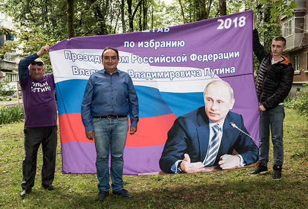 Марат Динаев (в центре) на фоне флага «Отрядов Путина»