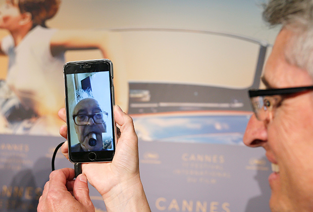 Продюсер Фабрис Араньо держит свой смартфон во время пресс-конференции с Жан-Люком Годаром 12 мая 2018 года на Каннском фестивале.