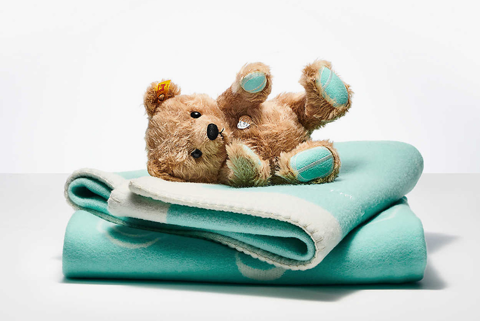 Милый символический подарок для новорожденного: мишка Тедди с пяточками фирменного бирюзового оттенка Tiffany и серебряным сердечком с узнаваемой гравировкой. Легкое одеяльце все того же бирюзового цвета — идеальное дополнение.