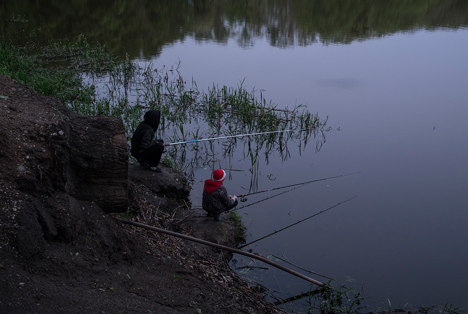 Отец с сыном ловят рыбу в озере. Рыбалка — одно из немногих семейных развлечений в поселке.