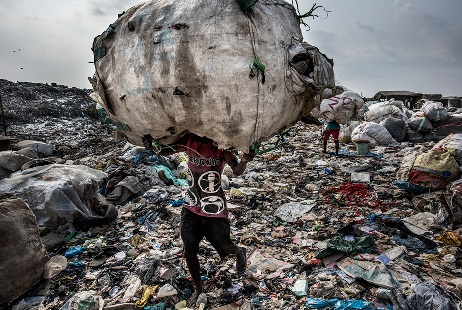 Мусорный кризис постепенно окутывает всю планету. Люди производят столько отходов, сколько никогда прежде не производили. Ежедневно в мире появляется 3,5 миллиона тонн твердых отходов, что в 10 раз превышает уровень прошлого столетия. Только американцы ежемесячно отправляют на свалку мусор, равный весу своего тела. Такими темпами к концу XXI века ежедневный объем отходов на планете может достигнуть 11 миллионов тонн. 




Мусорный коллапс во всех красках оказался в объективе нидерландского фотографа Кадира ван Лохёйзена. Он изучил, как проблема с мусором решается в шести крупных мегаполисах мира — Джакарте, Токио, Лагосе, Нью-Йорке, Сан-Паулу и Амстердаме. Фотограф пришел к выводу, что до сих пор далеко не все осознают, что отбросы можно использовать вторично.




Лидером по отходам среди всех городов мира является Нью-Йорк: 33 миллиона тонн в год, что в 15 раз превышает показатель Лагоса, в котором, однако же, проживает гораздо больше людей. На снимке — один из пяти тысяч работников лагосской свалки Олусосан, занимающей 45 гектаров. Среди гор мусора они ищут пластик и другие материалы, которые можно отправить на переработку.




Ежедневно на Олусосан свозят от трех до пяти тысяч тонн мусора. Полигон переполнен, и городские власти планируют его закрывать. Однако другой свалки нет, а инфраструктуры для переработки отходов недостаточно. Лохёйзен подмечает, что нигерийские свалки пахнут значительно меньше, чем другие подобные по всему миру, поскольку жители страны выбрасывают меньше продуктов. Они либо все доедают, либо отдают оставшееся животным.