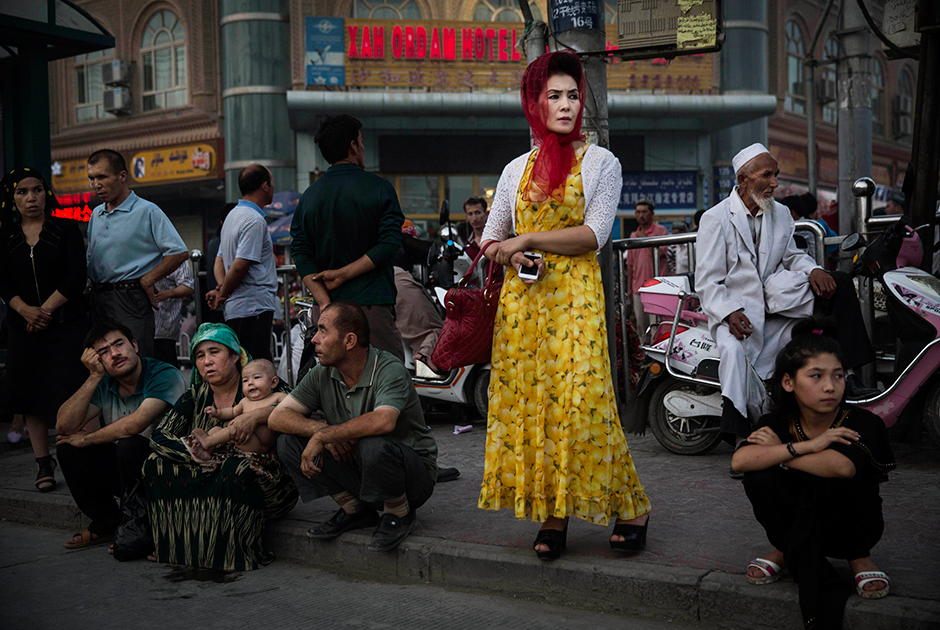 Кашгарцы в ожидании автобуса. Китайские власти регулярно проводят пропагандистские кампании среди местной молодежи, призывающие отказаться от ношения бороды и национального костюма. Тем не менее большинство кашгарцев остаются верны традициям.