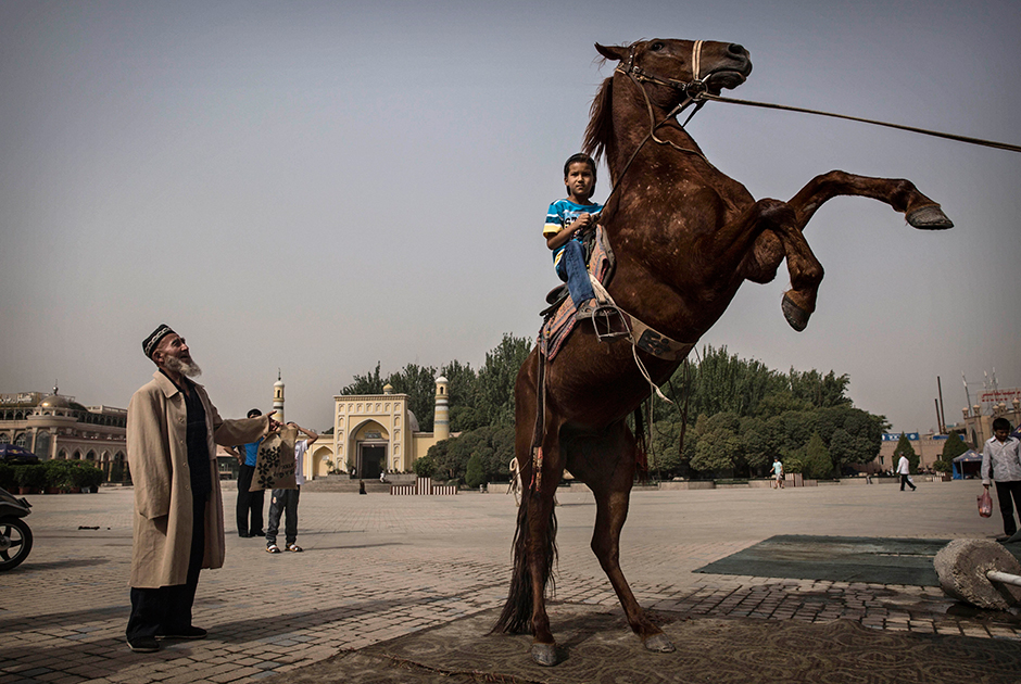 Уйгурский мальчик гарцует на лошади напротив главной достопримечательности Кашгара — мечети Ид Ках, крупнейшей в Китае. Она была построена в 1442 году, многократно перестраивалась и сейчас вмещает до 20 000 молящихся.   