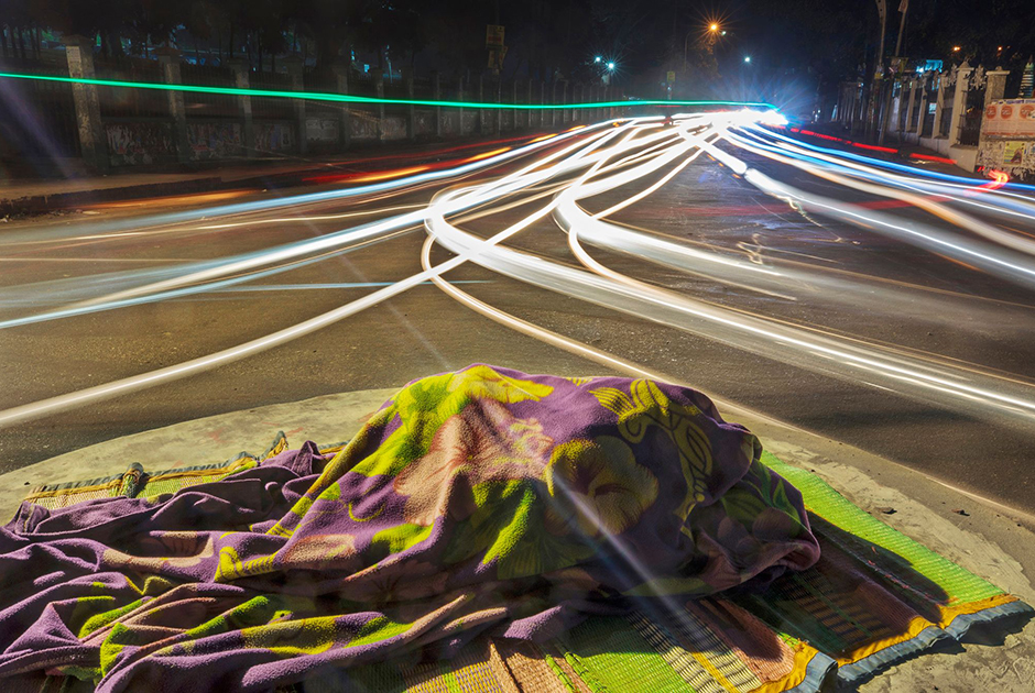 20-летняя Амена выросла на тротуарах, ночуя в парках. Сейчас она не может найти приют в городских зеленых зонах из-за запрета правительства. Поэтому ей приходится спать на разделительных полосах, либо на перекрестках с круговым движением. Фотография сделана в городе Читтагонг в Бангладеш. Изображение из проекта «Плывущие герои», получившего первый приз в категории «Серия».