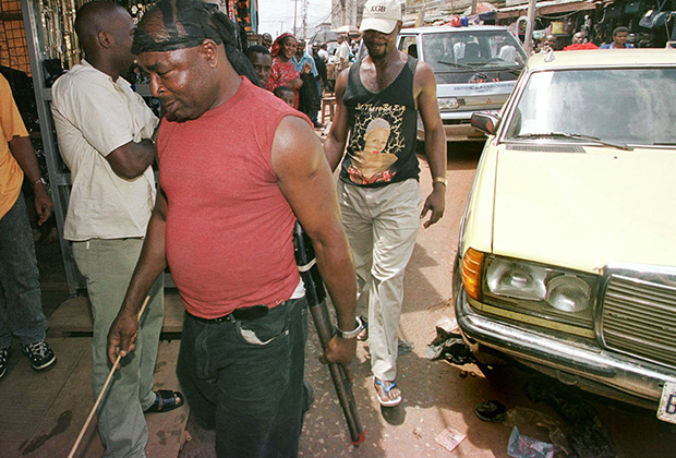 Боец банды «Парни из Бакасси» патрулирует город с обрезом и палкой, 2002 год