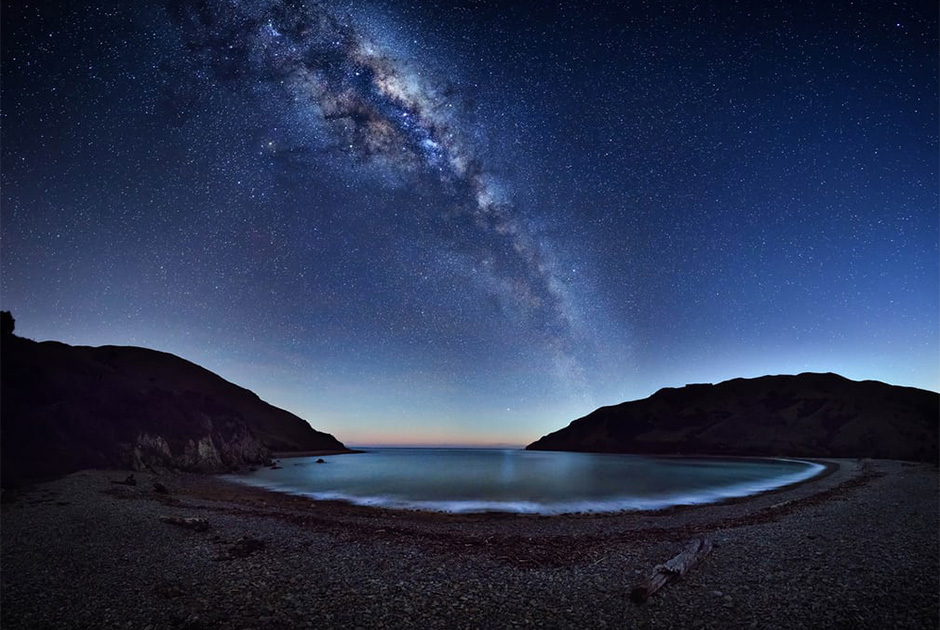 Млечный Путь простирается через ночное небо, отражаясь в воде залива Кейбл Бэй (Новая Зеландия). Для создания панорамы были использованы 42 отдельных изображения.
