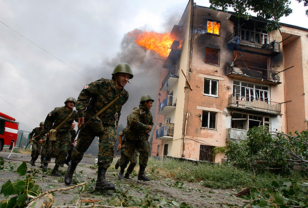Грузинские солдаты в Гори на фоне здания, пострадавшего от бомбардировки. 9 августа 2008 года