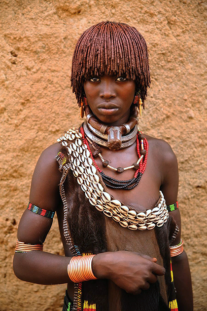Хамер — это народ, населяющий плодородную часть долины реки Омо, так называемую зону Дебуб в юго-западной Эфиопии. Из 46 тысяч людей племени хамер только семь окончили среднюю школу. Это скотоводы, владеющие большим количеством крупного рогатого скота. Полигамия является частью их культуры, мужчина часто имеет более одной жены. У первой жены более высокий статус. У женщины на фото — несколько ожерелий. Верхнее, с выступом, символизирует то, что она является первой женой. Всего жен три — по количеству ожерелий. Фото сделано на рынке в главном поселке территории хамеров — Турми, когда женщина просто пришла на рынок из своей деревни. 