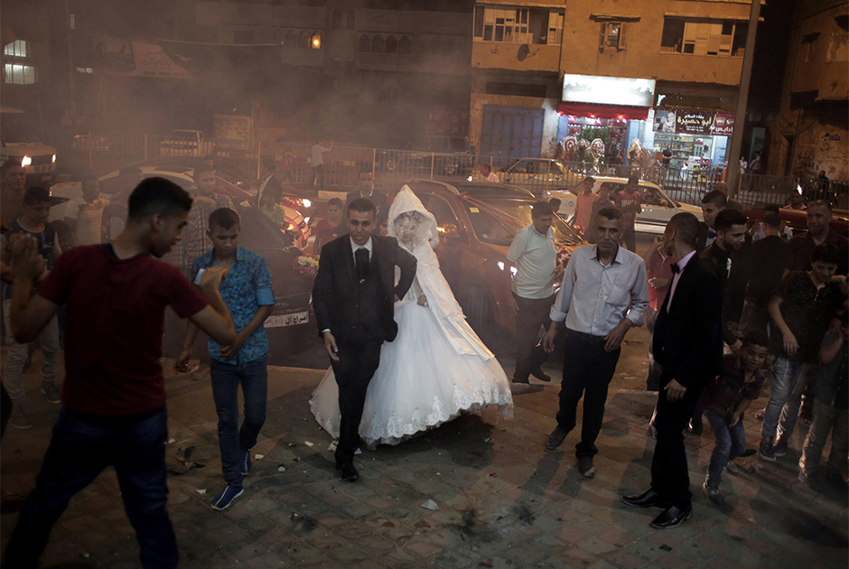 Молодожены Саед Абу Асер (Saed Abu Aser) и Фаластин (Falasteen) проходят сквозь дым от фейерверков в день бракосочетания. Свадьбы стали редкими радостными событиями, которые могут разбавить мрачное существование в секторе Газа. Фотограф Халил Хамра называет эту небольшую территорию своей большой страстью. Его привлекает буйство чувств: страдания, боль, голод, нищета и другие трагедии человеческой жизни — все это на 360 квадратных километрах делят между собой несколько миллионов человек.