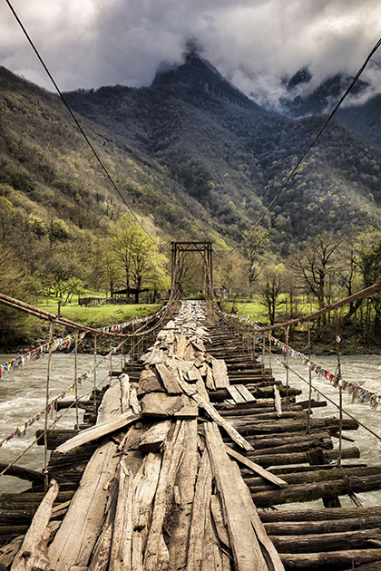 Шаткий деревянный мост над рекой Бзыбь раскачивается не только ветром, но и топотом туристов, которые заезжают сюда в поисках острых ощущений по дороге на озеро Рица и Гегский водопад.