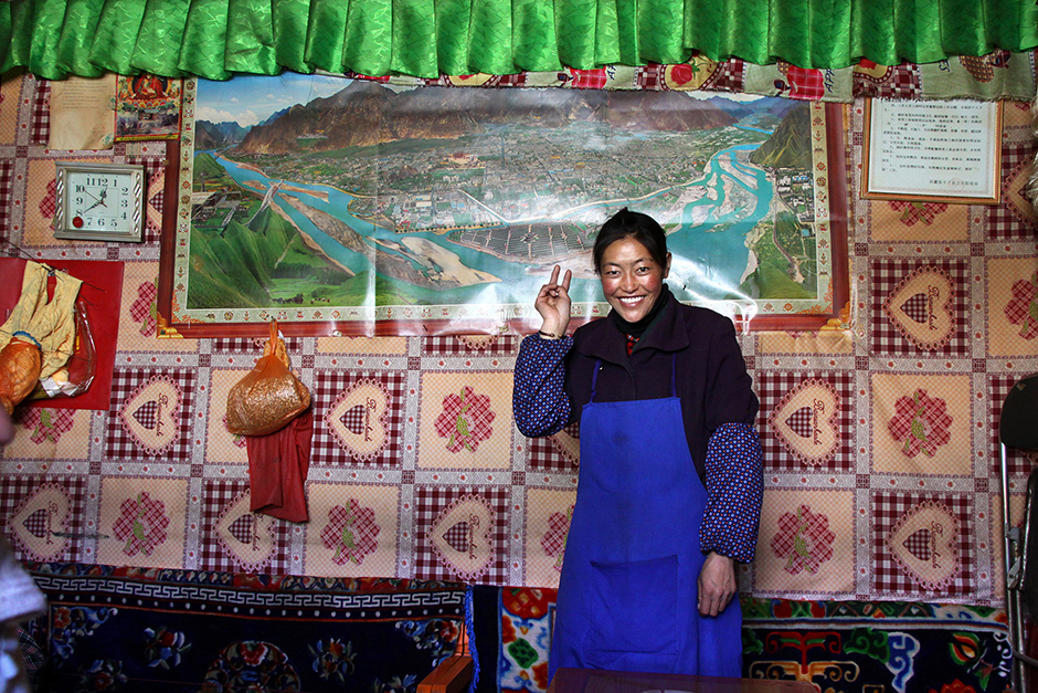 А это Тибет, город Гьянце. Местная жительница позирует на фоне изображения Лхасы. 