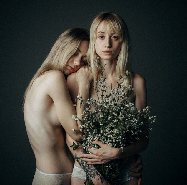Фотограф из России Даниил Прокопенко решил показать образ тишины через снимок двух обнимающихся полуобнаженных девушек. В руках одной из них — большой букет увядших ромашек, который прикрывает интимные части тела.