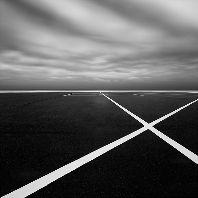 Японский фотограф Хиронори Накамура создал серию минималистичных фотографий с автомобильной парковки. По его словам, симметричные линии белой краски создают на фотографиях особый ритм. 