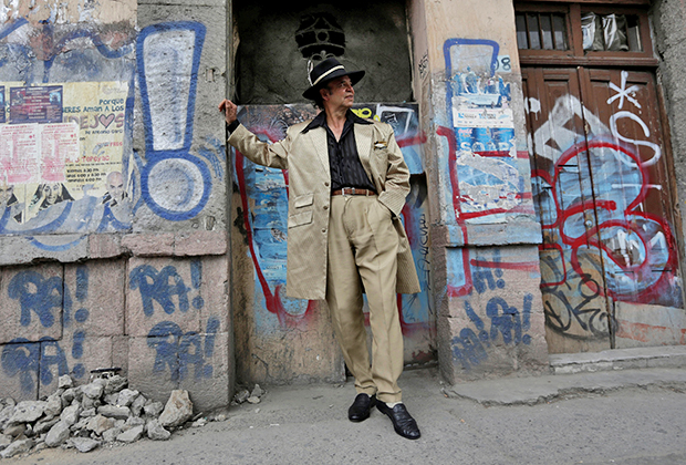 Житель Мехико Даниэль Родригес, одетый в стиле пачукос, позирует на фоне расписанной в традиционном стиле стены в Мехико. 

