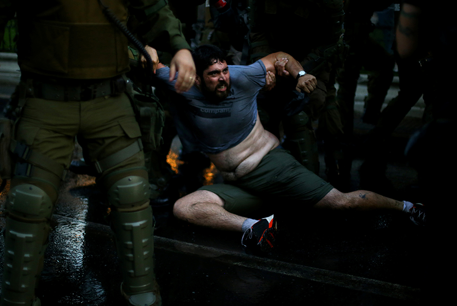 Задержание демонстранта во время акции протеста в столице Чили — Сантьяго. Протестующие требовали положить конец спекуляциям в системе образования.