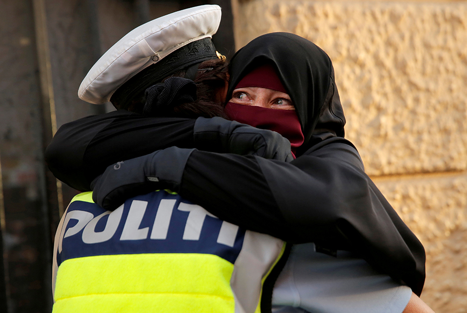 37-летняя Айя в хиджабе плачет, обнимая полицейского во время демонстрации  против запрета на ношение закрывающих лицо никабов в Дании.
