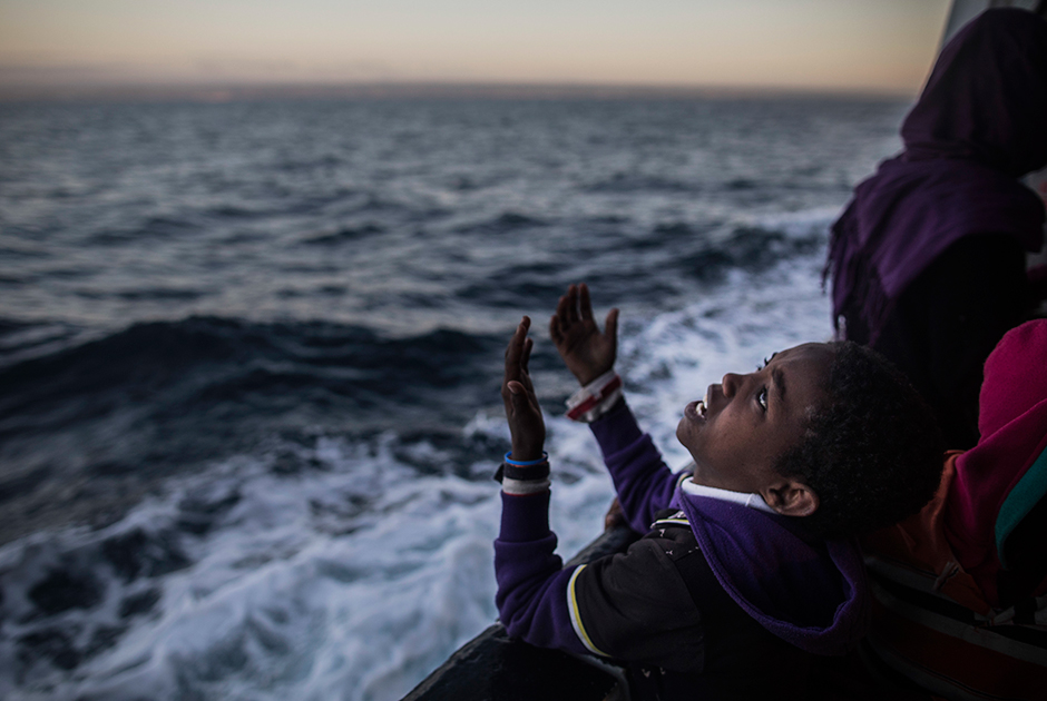 Мальчик поет от радости по пути из Эритреи в Европу. Его везут на борту испанского спасательного судна общественной организации Proactiva Open Arms. Участники этого объединения занимаются поиском и спасением людей в море. Фото сделано 18 января 2018 года у берегов города Поццалло на Сицилии.