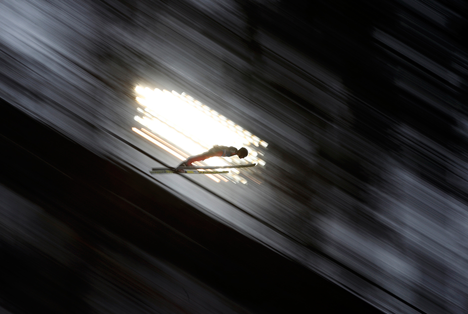 Спортсмен совершает пробный прыжок на лыжах с трамплина. Фото сделано в австрийском городе Бишофсхофен во время Турне четырех трамплинов.