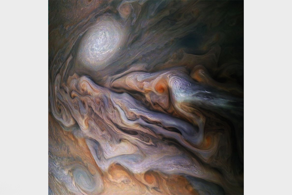 Межпланетная станция Juno уже восемь лет изучает Юпитер, получая богатые данные и снимки газового гиганта. Вихрящиеся облака и большой ураган — белый овал на фотографии — располагаются в северном полушарии планеты.