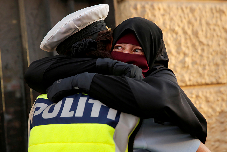37-летняя Айя расплакалась, когда во время демонстрации против запрета на ношение никабов в Дании ее обняла женщина-полицейский.


Фотография вызвала резонанс в датском обществе. Одни обвиняли женщину-полицейского в том, что та не оштрафовала нарушительницу, и призывали к ее отстранению. Другие хвалили офицера за толерантность и человечность. Ситуация спровоцировала интерес к Айе. Она дала множество интервью, в которых рассказала, как нововведение ограничивает ее свободу. В конце концов она была вынуждена самоустраниться из публичного пространства из-за полившегося в ее сторону негатива.
