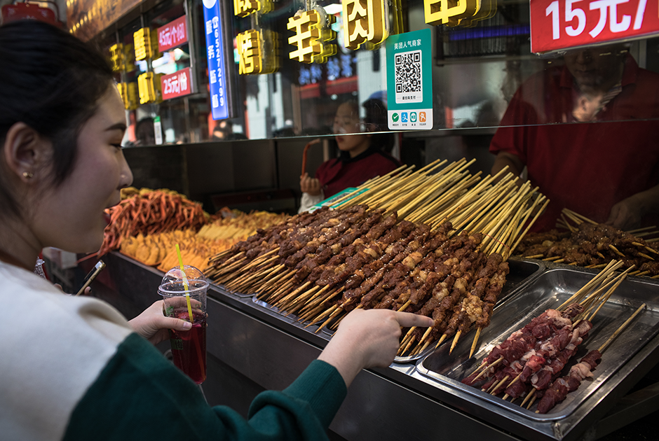Улица Ванфунцзин — одна из самых популярных торговых улиц Пекина, знаменитая в том числе своим стритфудом. Здесь можно найти блюда из всех регионов Китая. Например, женщина на фото выбирает чуань — уйгурский шашлык. Маленькие кусочки говядины нанизывают на шпажку, обваливают в специях (тмин, кунжутное масло и хлопья сушеного перца) и жарят на углях.
