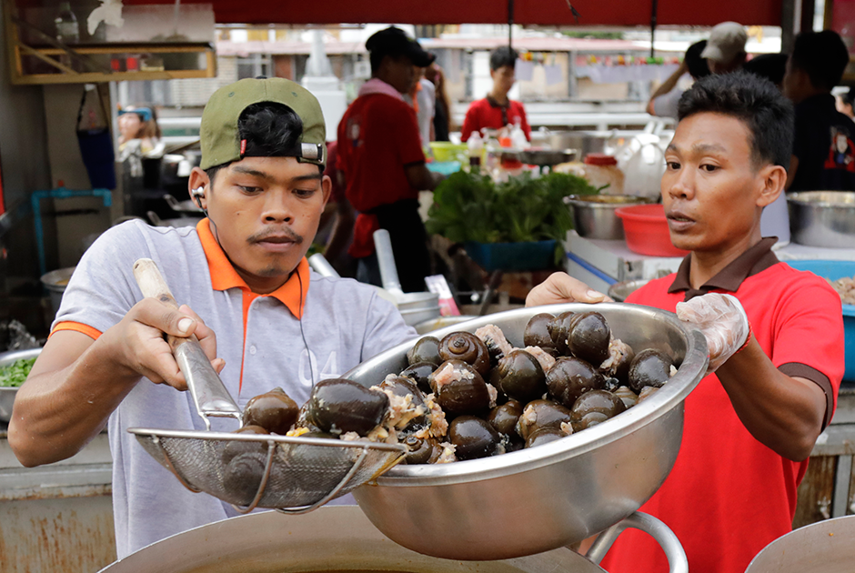 Уличные торговцы готовят суп из улиток на острове Кох-Пич. Для него используют озерных улиток, собранных в провинциях вокруг Пномпеня, столицы Камбоджи. Улитки — популярный ингредиент камбоджийской кухни, который применяют для многих блюд. Попробовать их в туристических местах сложно — гостям чаще предлагают китайскую и вьетнамскую кухни, более известные в мире.  