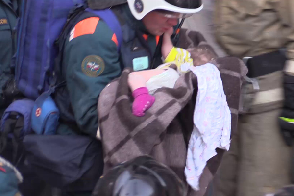 Извлеченный из-под завалов ребенок на руках спасателя