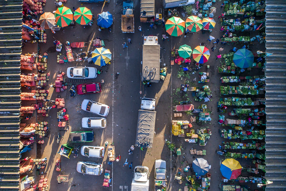 Алекс Висбал известен симметричными снимками хаотичных улиц, оживленных шоссе и автобусных остановок. Фотография шумного многолюдного рынка в Колумбии имеет четкое цветовое разграничение из-за контрастных товаров, которые продаются с разных сторон улицы. Отсюда и название — «Зеленые и красные».
