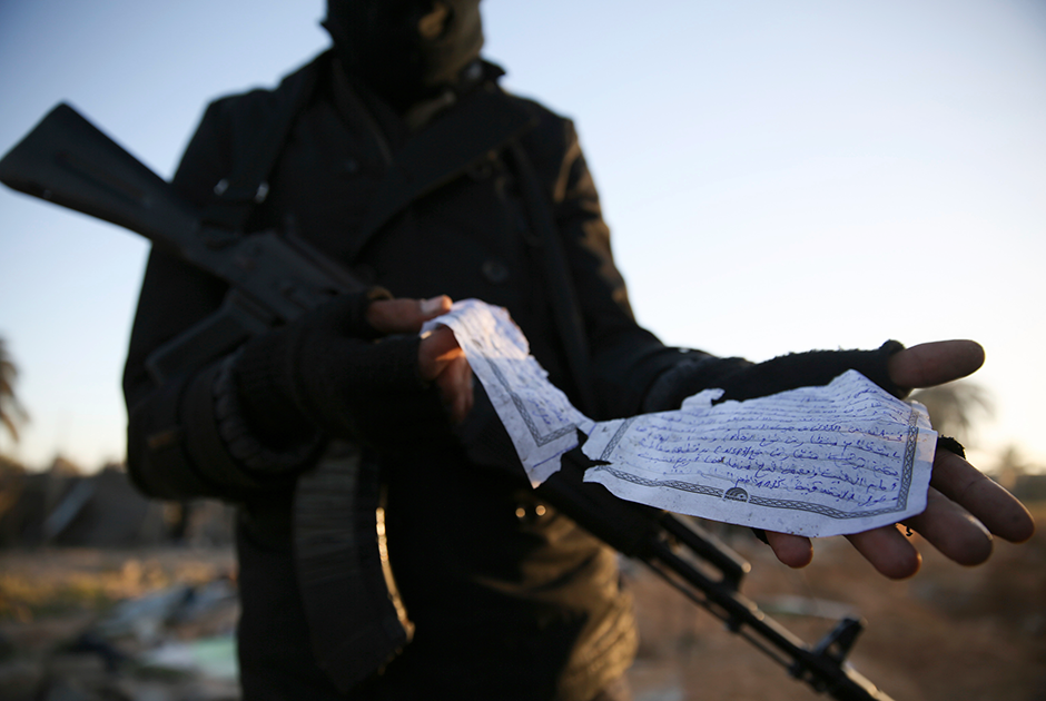 Сотрудник правительственных сил Ливии демонстрирует бумажку, на которой на арабском языке описывается вооружение. Документ был найден на месте, по которому был нанесен авиаудар США в рамках уничтожения лагеря боевиков запрещенного на территории России «Исламского государства». В результате погибли десятки людей.
