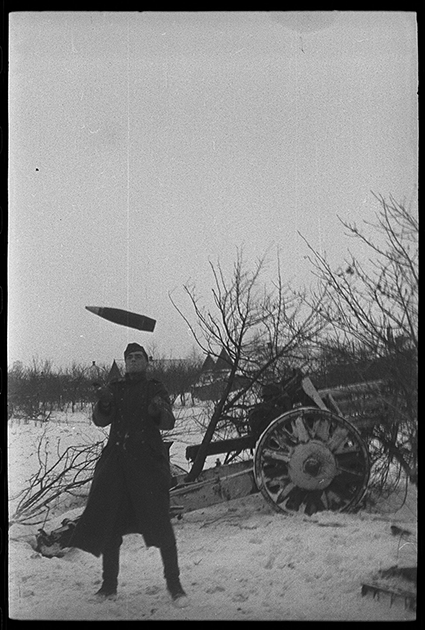 Артиллерист играет со снарядом возле немецкой легкой полевой гаубицы. Украина, 1941 год.