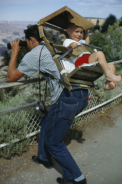 Пока отец наслаждается видом каньона в бинокль, сын развлекает сам себя в кресле-переноске, закрепленной на спине родителя. 
