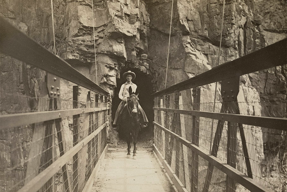 Всадник верхом на муле пересекает каньон по подвесному мосту Кайбаб, который также известен, как Черный мост. Он был построен в 1928 году. Все материалы были доставлены к месту строительства на мулах и спинах индейцев хавасупай. Около 1930 года. 